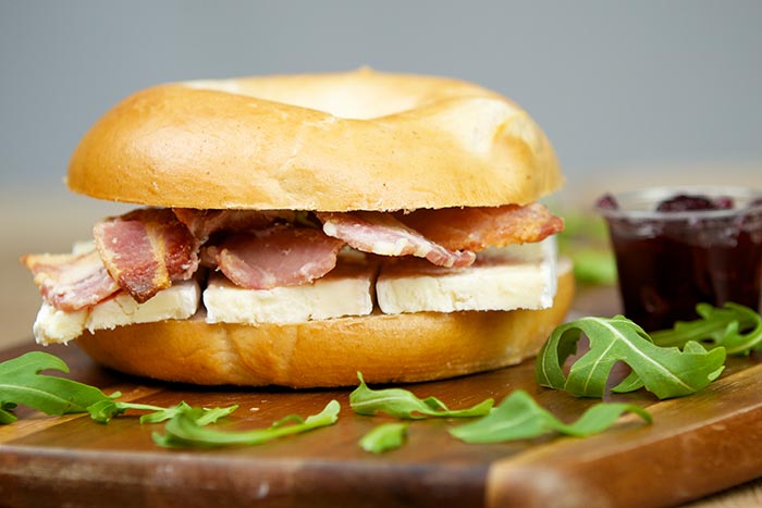 Bagel with bacon, brie cheese, and arugula garnish