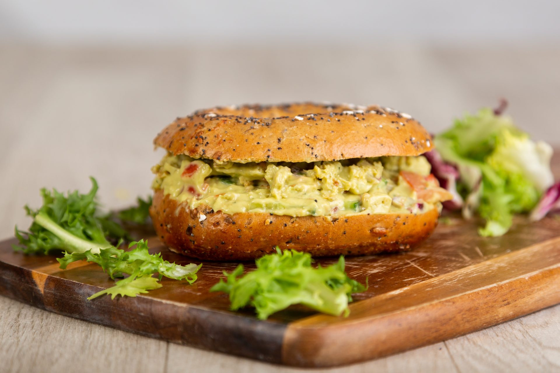 Bagel stuffed with guacamole and fresh salad greens