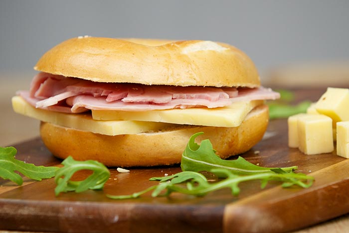 Bagel with ham and cheese, garnished with arugula