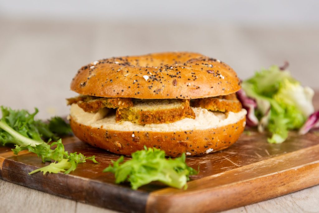 Bagel with falafel and hummus, garnished with greens