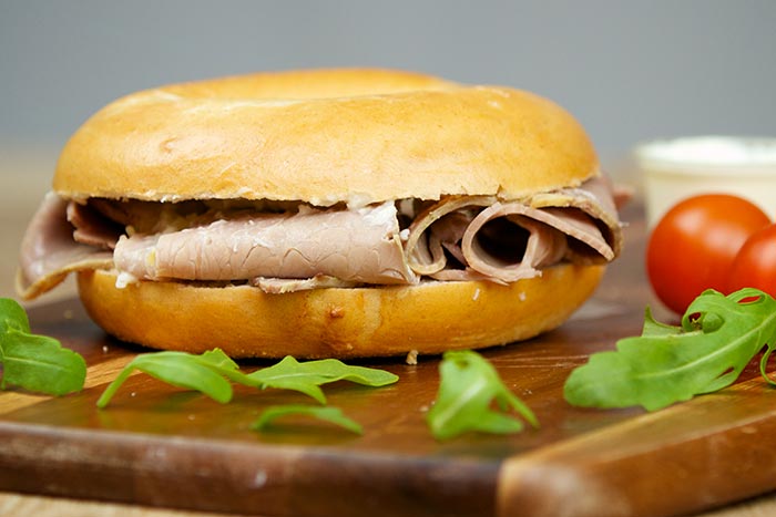 Bagel sandwich with roast beef and arugula garnish