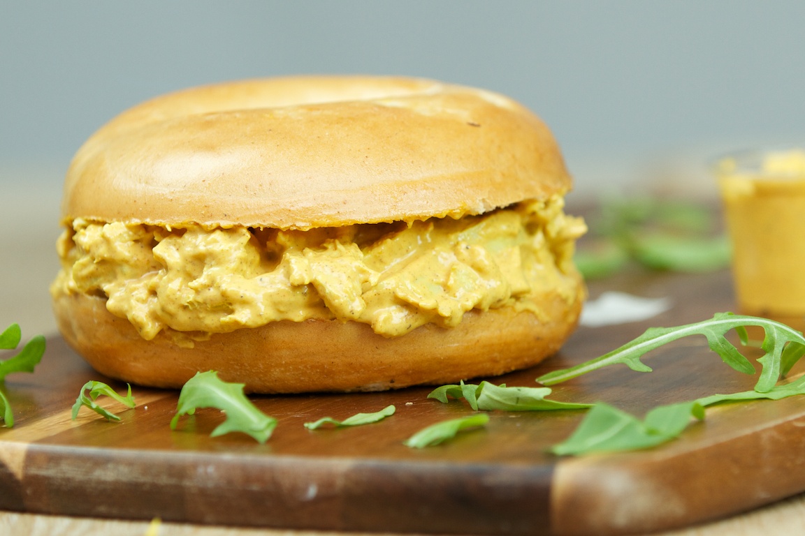 Bagel filled with creamy chicken curry salad and arugula